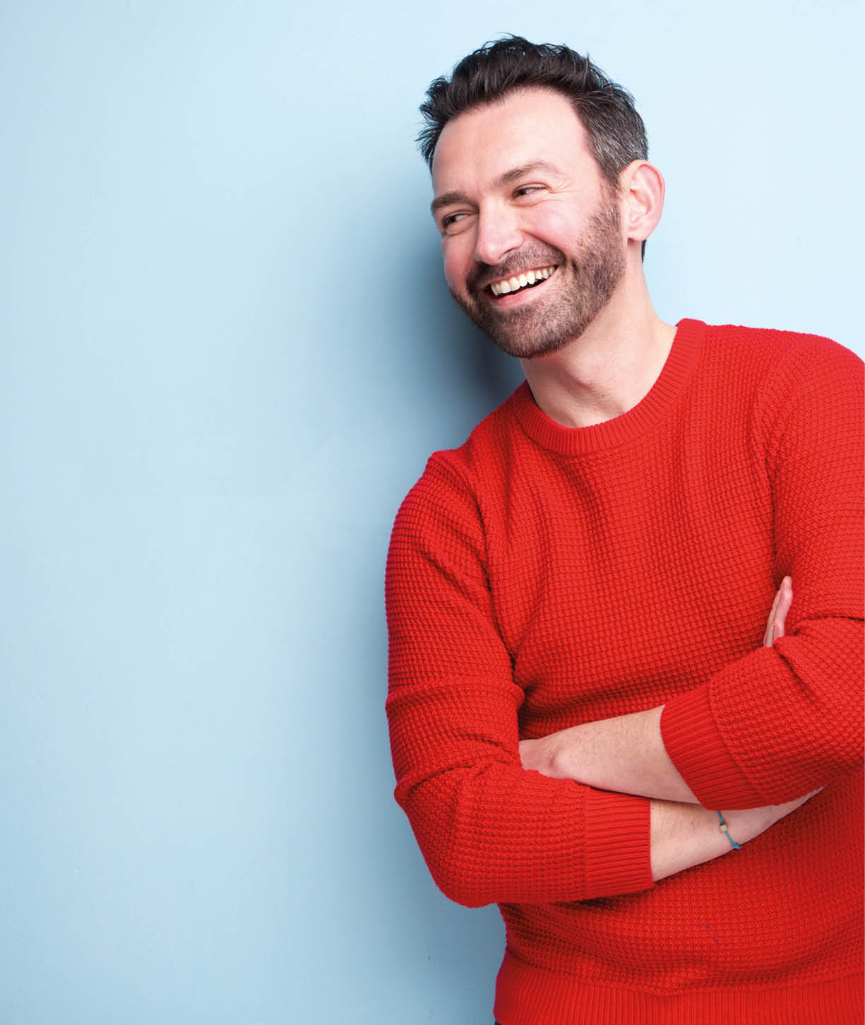 Portrait of cheerful man with beard laughing against blue background