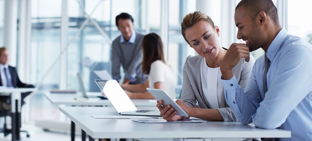 Business colleagues discussing over digital tablet at desk in office