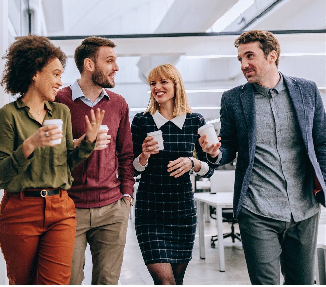 Group of diverse coworkers walking through a corridor in an office, holding paper cups