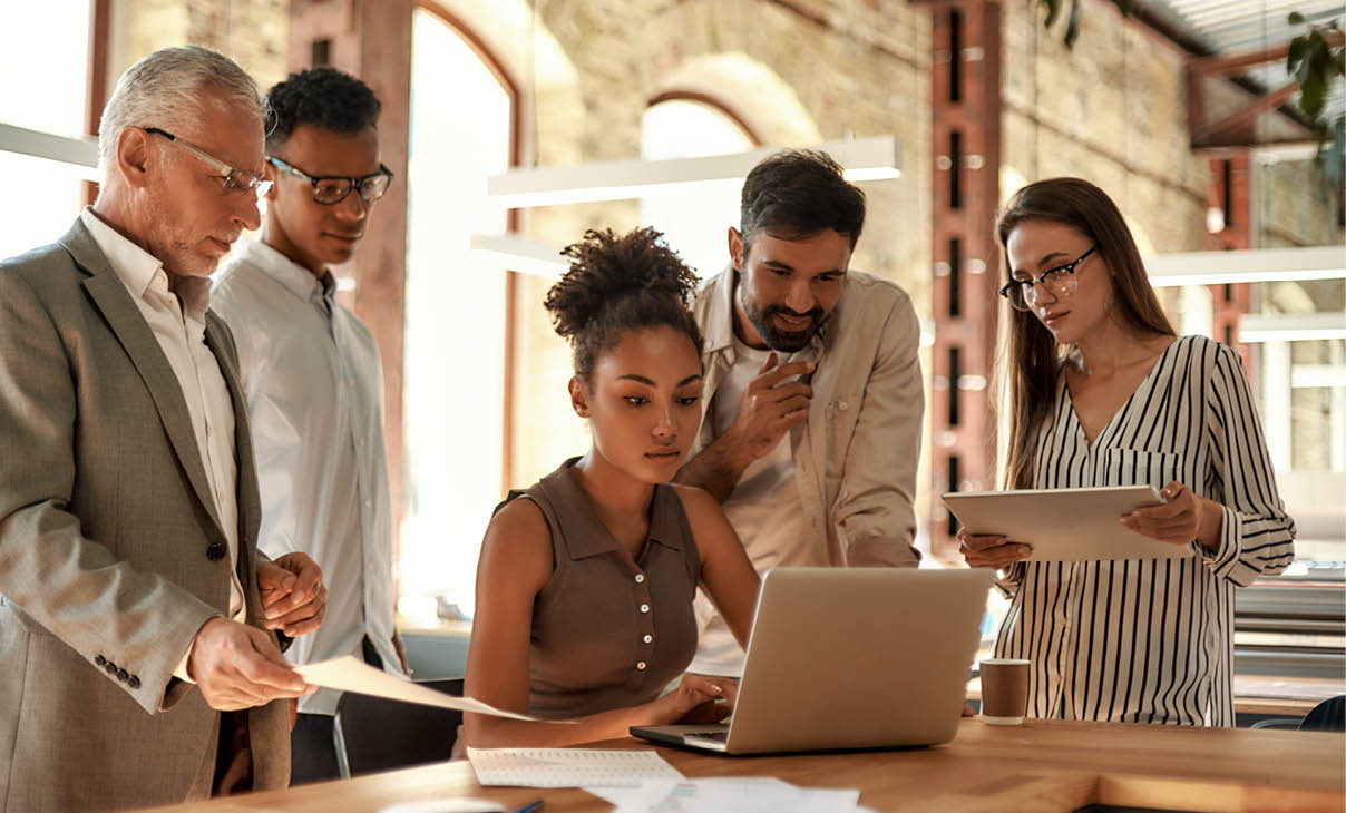 Project team. Multicultural team looking at the laptop and discussing project results while working together in the modern office. Teamwork. Office life