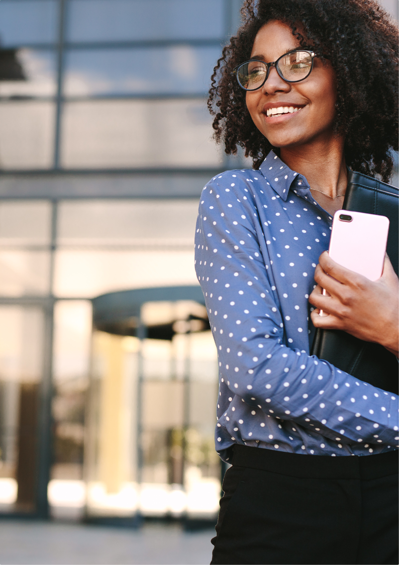 A person wearing glasses and a blue polka dot shirt is smiling and standing in front of a modern glass building.

Description generated by AI